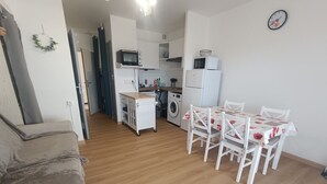 Ein kompakter Wohnbereich mit Küchenzeile, einem Essbereich mit Tisch und Stühlen sowie einer Couch.