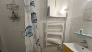Ein Badezimmer mit Duschvorhang, Handtuchhalter, Spiegel, Waschbecken und Toilette.