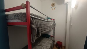 Ein Schlafzimmer mit Etagenbett, rotem Gestell, einem kleinen Hocker und einer Wanddekoration.