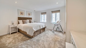 Une chambre à coucher avec un grand lit, des tables de chevet, une chaise et une fenêtre.