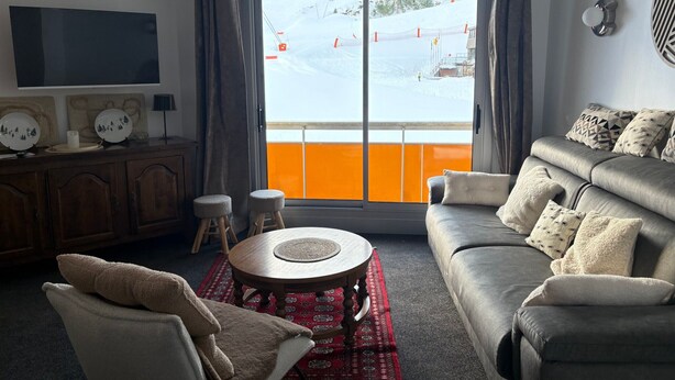 A living room with a sofa, a coffee table, a TV, and a view of a snowy landscape through a large window. - Gourette - Apartment 8 pers, South Balcony, Linens included, Pets allowed (Gourette)