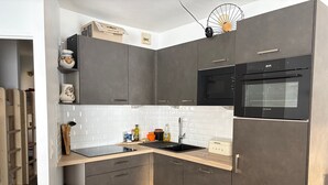 A modern kitchen with dark grey cabinets, a black microwave, and a stainless steel refrigerator. - Gourette - Apartment 8 pers, South Balcony, Linens included, Pets allowed (Gourette)