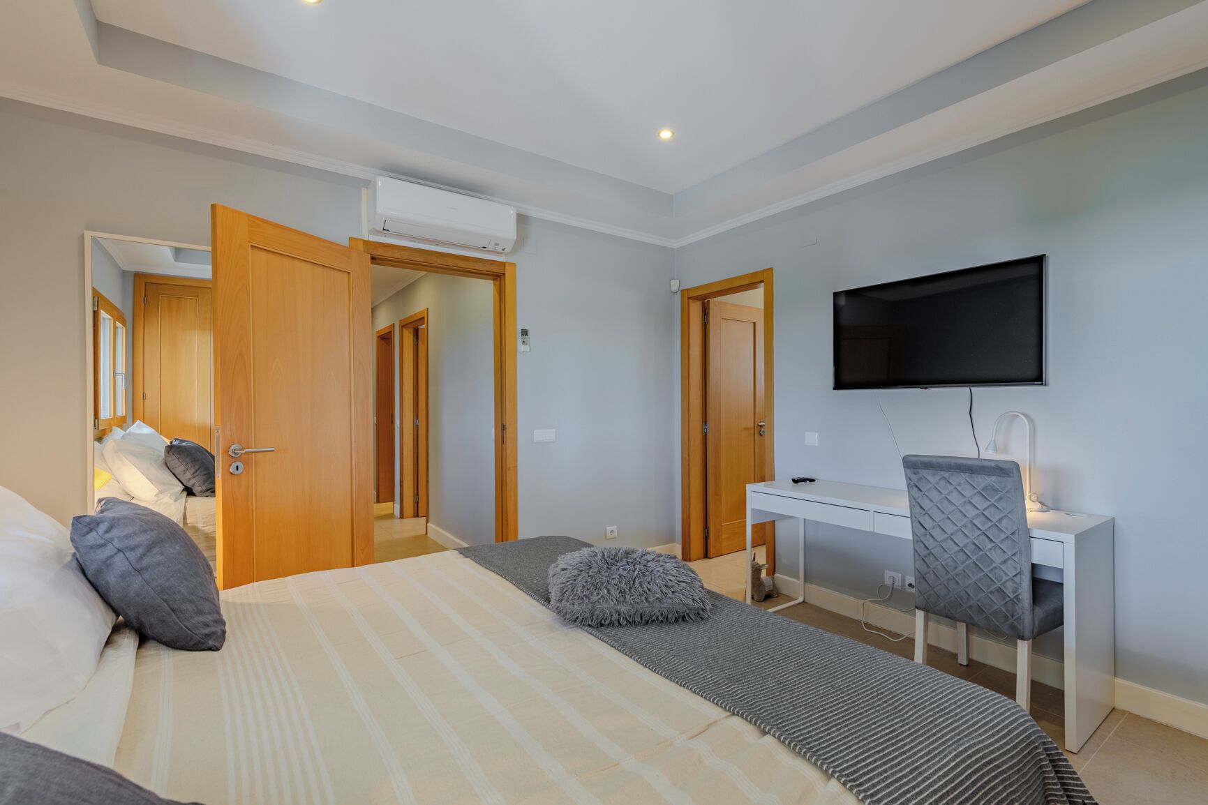 Ein Hotelzimmer mit Bett, Schreibtisch, Sessel, Fernseher und Klimaanlage.