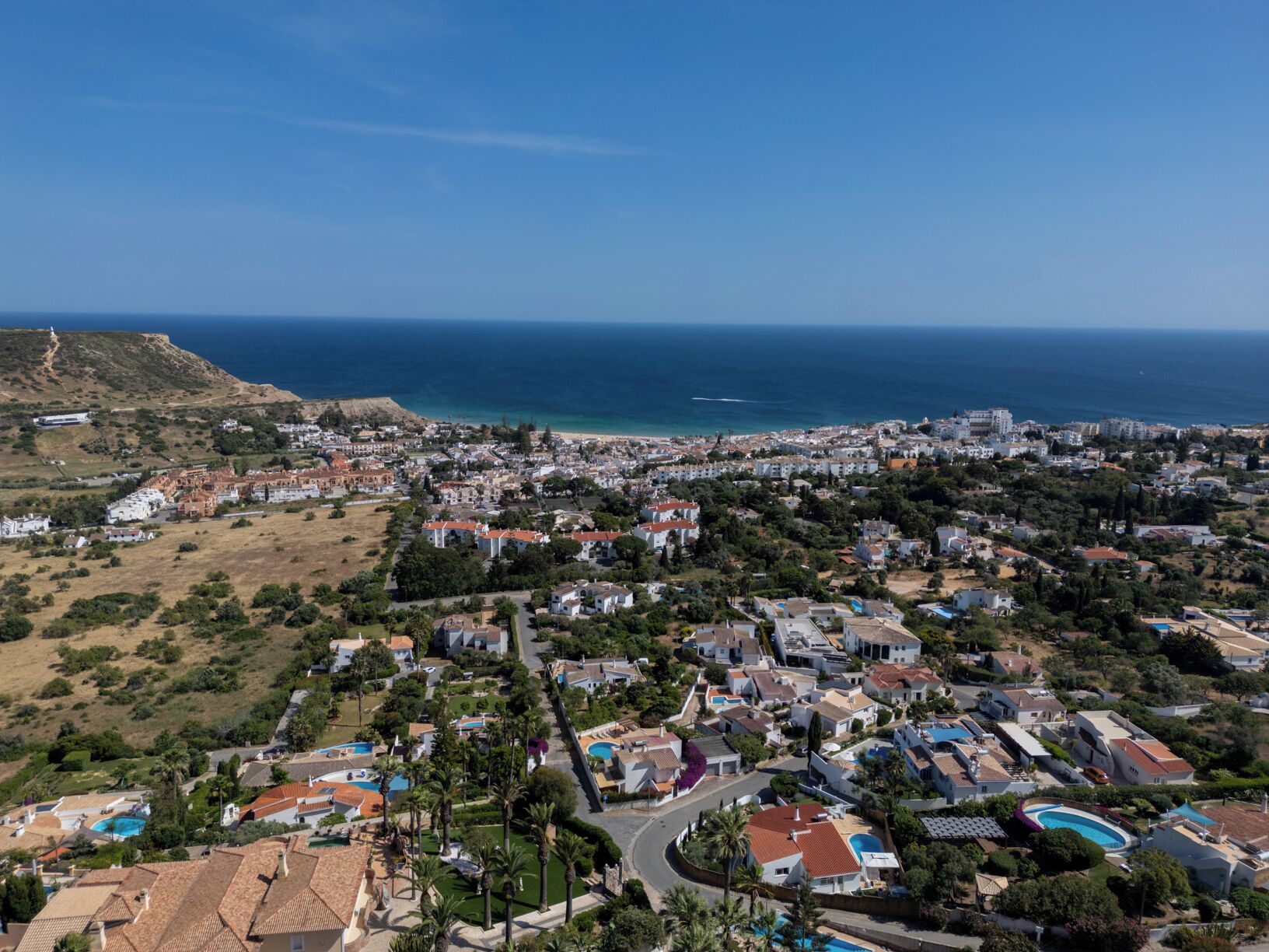 A coastal town with a mix of residential buildings, a prominent hill, and a beach.
