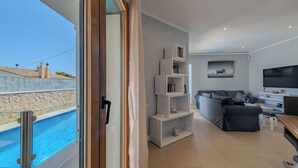 Ένα σύγχρονο σαλόνι με πισίνα, έναν καναπέ, μια τηλεόραση και μια βιβλιοθήκη.