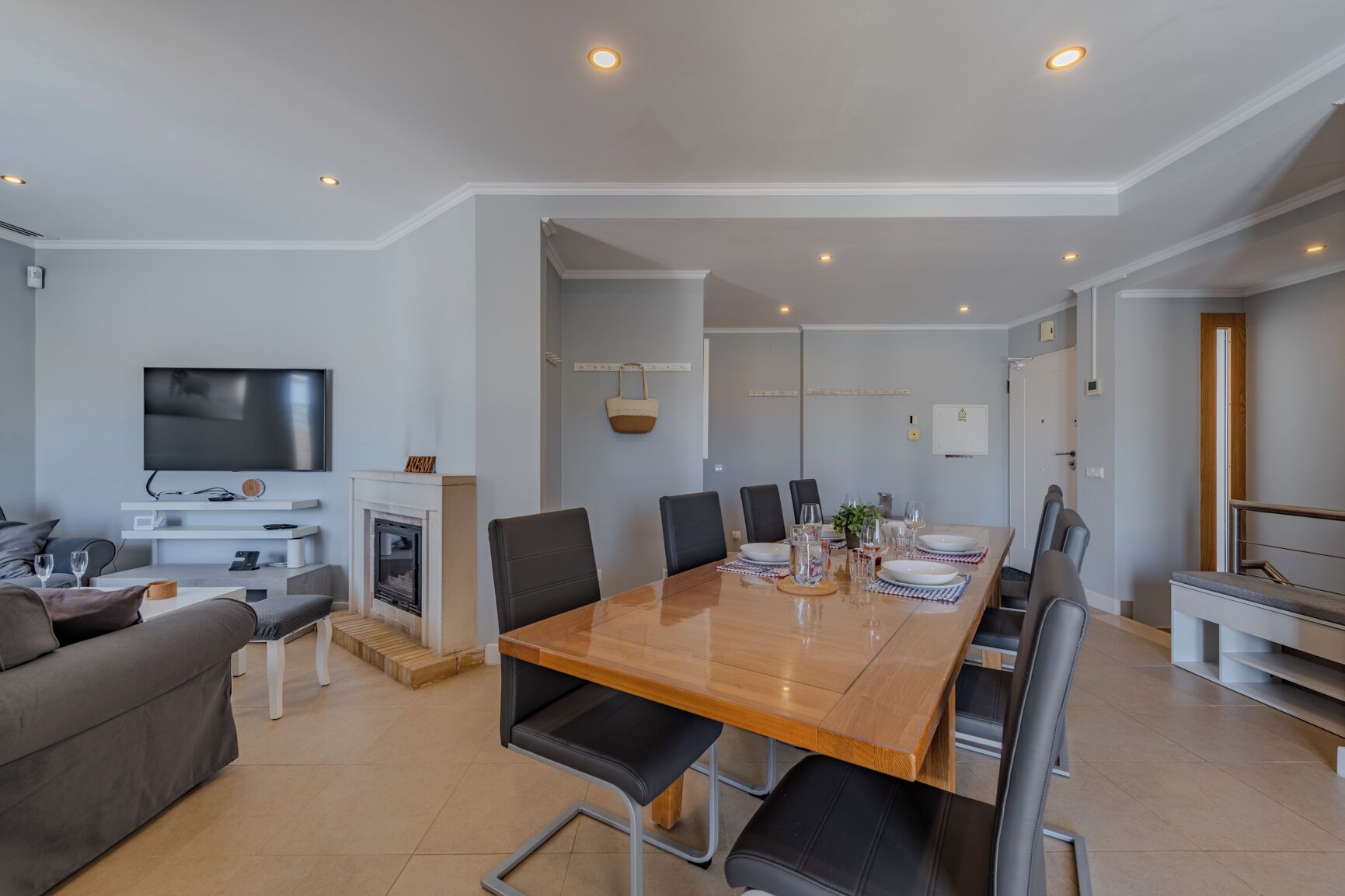 Un salon moderne comprenant un téléviseur, une cheminée, un canapé et un coin repas avec des chaises et une table.