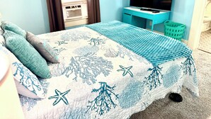 Ein Schlafzimmer mit Bett, Fernseher, Schreibtisch und Fenster.