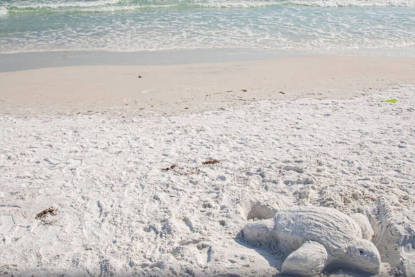 A sandy beach with footprints and a large sand formation.