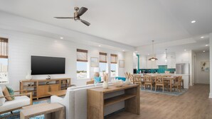 Ein modernes Wohnzimmer mit Flachbildfernseher, Holzmöbeln und Deckenventilator.