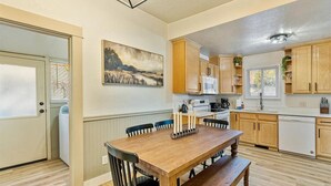 A kitchen with wooden cabinets, a dining table with chairs, and a painting on the wall. - Hot Tub Getaway and Quiet Home Near Downtown SLC (South Salt Lake)