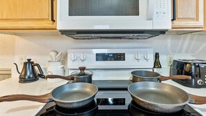 A kitchen with a microwave, stove, and two frying pans. - Hot Tub Getaway and Quiet Home Near Downtown SLC (South Salt Lake)