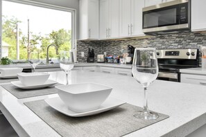 A modern kitchen with white cabinets, a black microwave, and a tiled backsplash. - Enjoyable 6-bedroom house with AC in vibrant Houston (Houston)