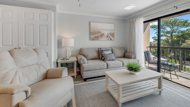 A living room with a sofa, a coffee table, a lamp, and a painting on the wall. - Decorated 1BR Condo at Ocean Dunes Tower 1 with Pool (Myrtle Beach)