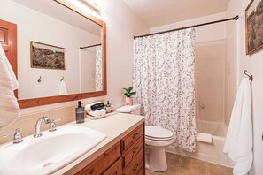 A bathroom with a sink, toilet, shower, and a mirror. - Fabulous 6-bedroom farmhouse in charming Ririe, perfect for groups! (Ririe)