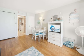 A modern living room with a dining area, a fireplace, and a sign for Big Fish Rentals. - New Direct Oceanfront View, Sandcastle South! (Myrtle Beach)