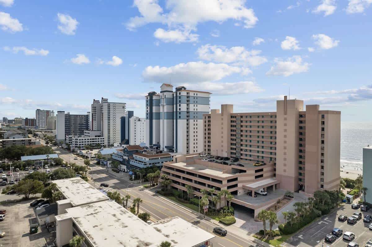 A high-rise hotel with multiple floors, a parking garage, and a view of the beach.