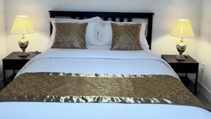 A neatly made bed with a patterned bedspread, two bedside lamps, and a headboard. - Experience 5-star comfort without the 5-star price tag. Peaceful Delta retreat  (Delta)
