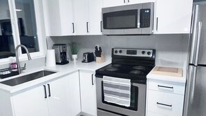 A modern kitchen with white cabinets, a stainless steel refrigerator, a microwave, a stove, and a sink. - Experience 5-star comfort without the 5-star price tag. Peaceful Delta retreat  (Delta)