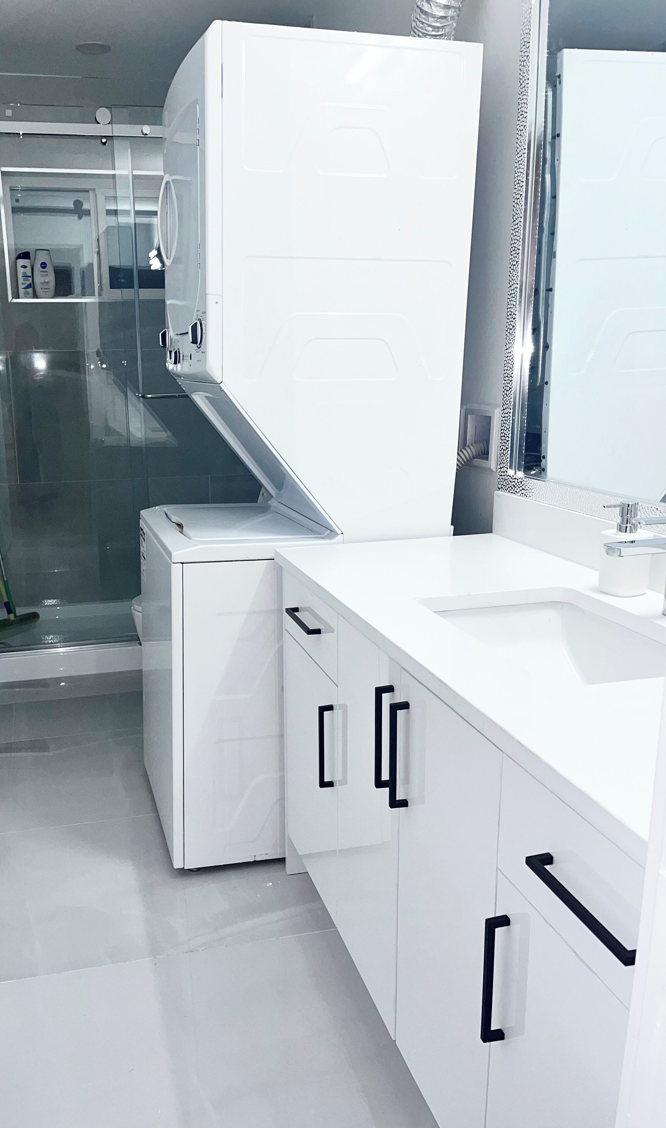 A modern bathroom with a white sink, mirror, and cabinets.