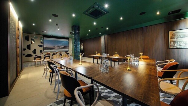 A conference room with a long wooden table, multiple chairs, and a large screen on the wall. - Gold Hotel Zlotoryja (Zlotoryja)