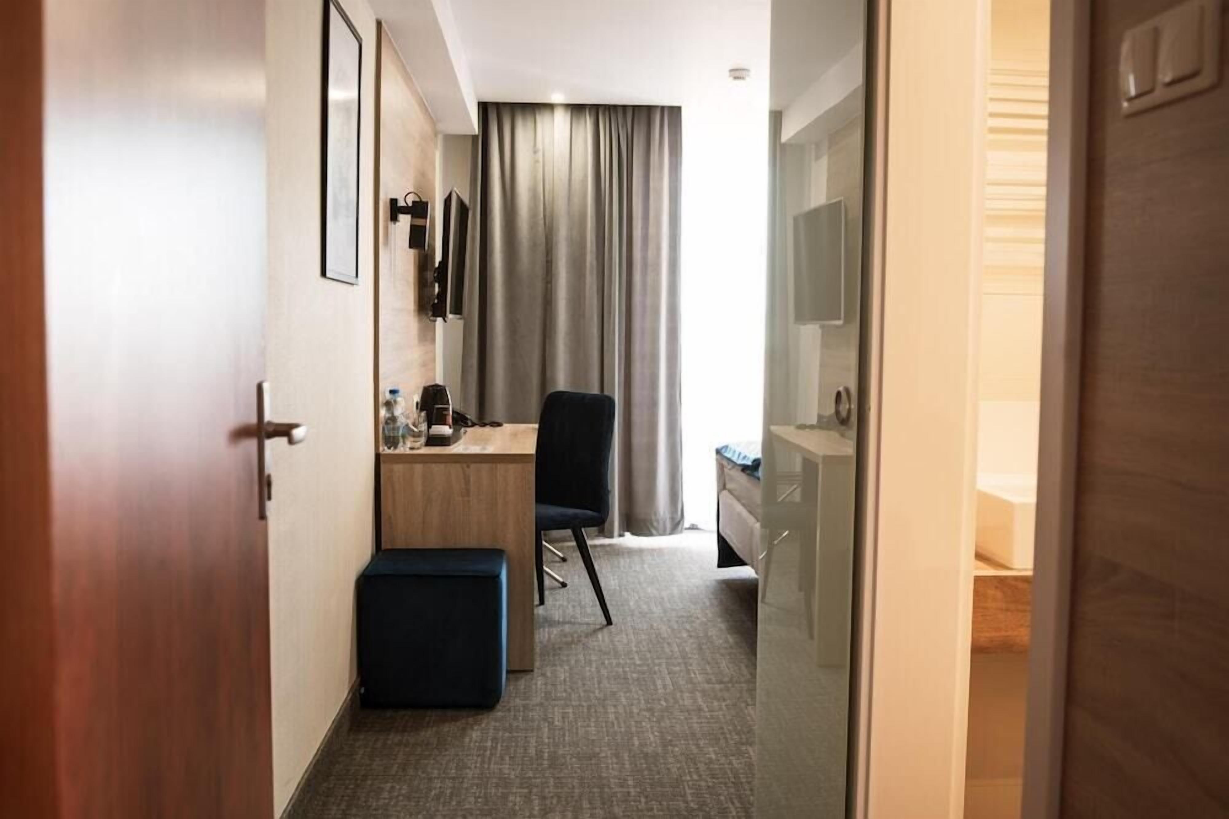A hotel room with a desk, chair, and a bed.