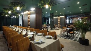 A restaurant with multiple dining tables and chairs, some with plants hanging above. - Gold Hotel Zlotoryja (Zlotoryja)