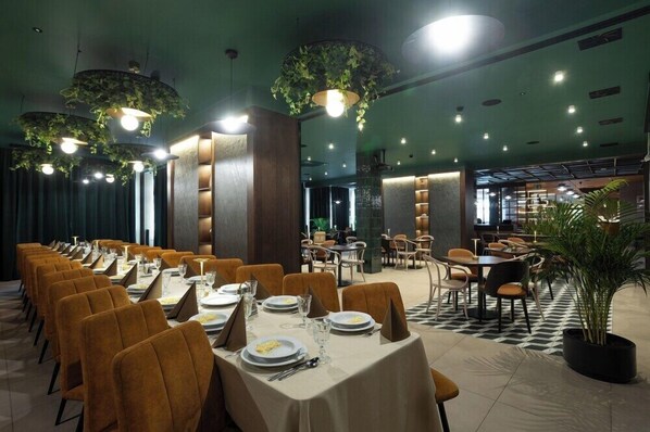 Een restaurant met meerdere eettafels en stoelen, waarvan sommige onderhangende planten hebben.