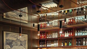 A bar area with a checkered floor, wooden bar counter, and stools. - Gold Hotel Zlotoryja (Zlotoryja)