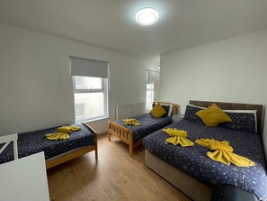 Una habitación con dos camas, una mesita y una ventana.