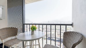Ein Balkon mit Korbstühlen, einem kleinen runden Tisch und einem Blumentopf.