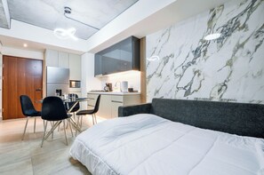 Habitació d'hotel moderna amb un llit, zona de menjador i cuina.