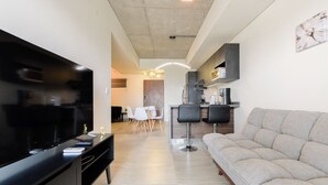 Ein modernes Wohnzimmer mit Flachbildfernseher, einer Couch und einem Essbereich mit Tisch und Stühlen.