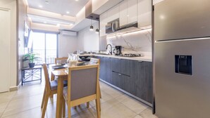 Eine moderne Küche mit integriertem Kühlschrank, dunklen Schränken und einem Essbereich mit Holztisch und Stühlen.