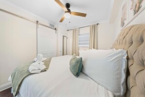 A bedroom with a bed, a ceiling fan, a window with curtains, and a door. - Seaside Beach & Racquet 3205 (Orange Beach)