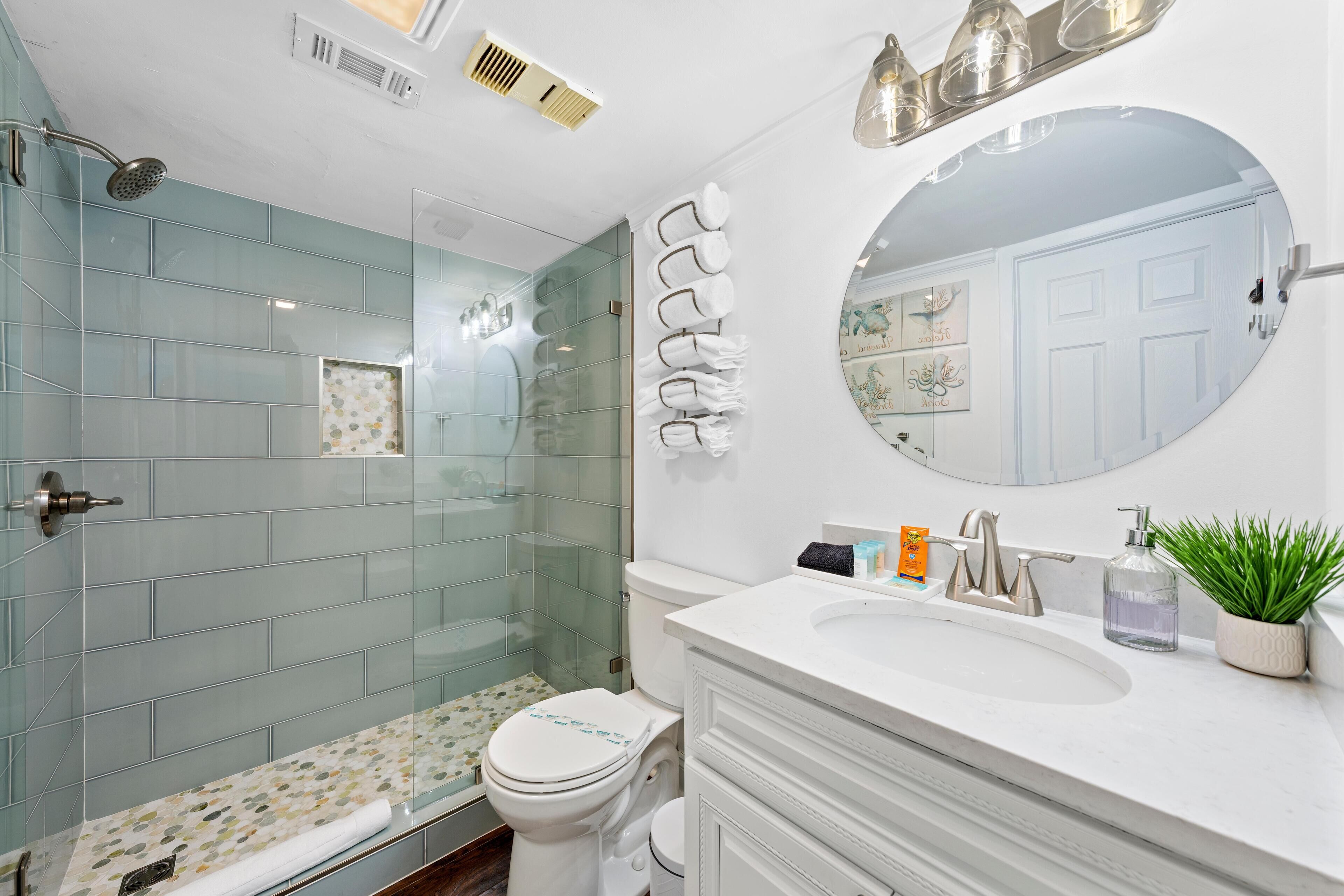 Ein Badezimmer mit Dusche, Toilette, Waschbecken und Spiegel.