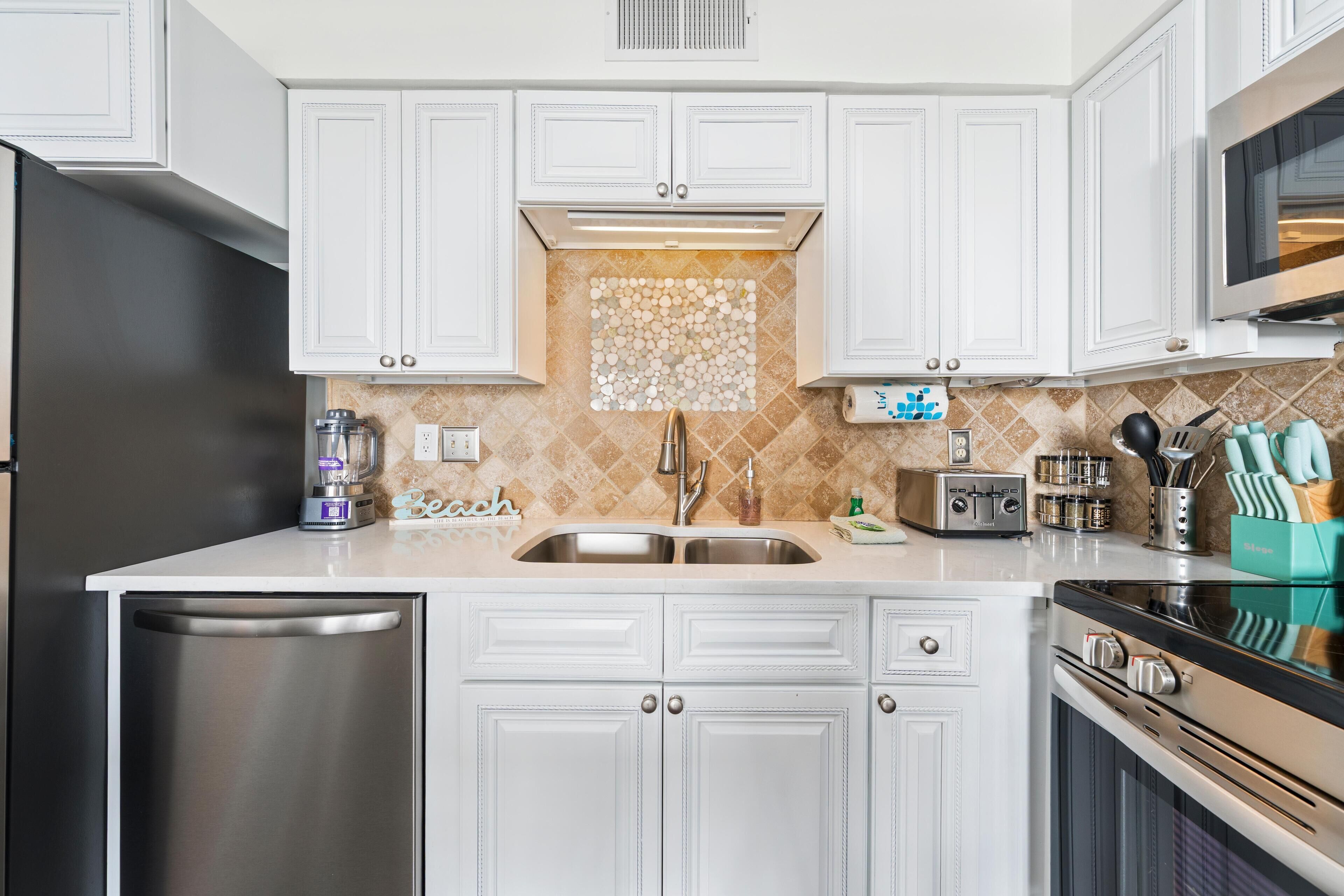 A modern kitchen with white cabinetry, stainless steel appliances, and a tiled backsplash.