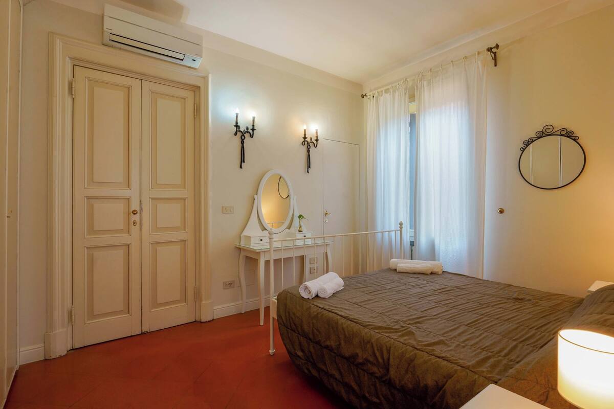 Un dormitorio con cama, cómoda, espejo y aire acondicionado.
