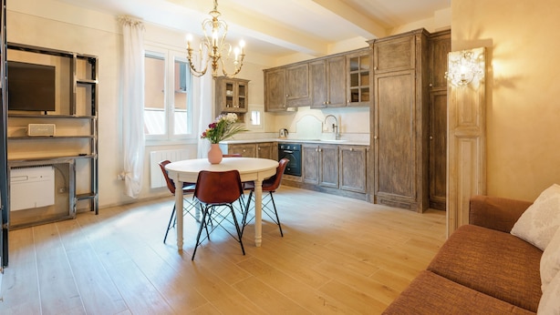 Una cocina amplia con armarios de madera, una mesa de comedor con sillas y una araña.