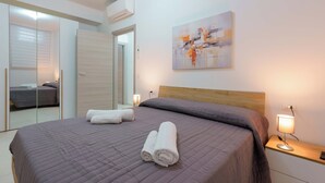 A bedroom with a bed, a bedside lamp, a wall-mounted abstract painting, and a mirror. - Casarossoblu- Zona Stadio (Bologna)