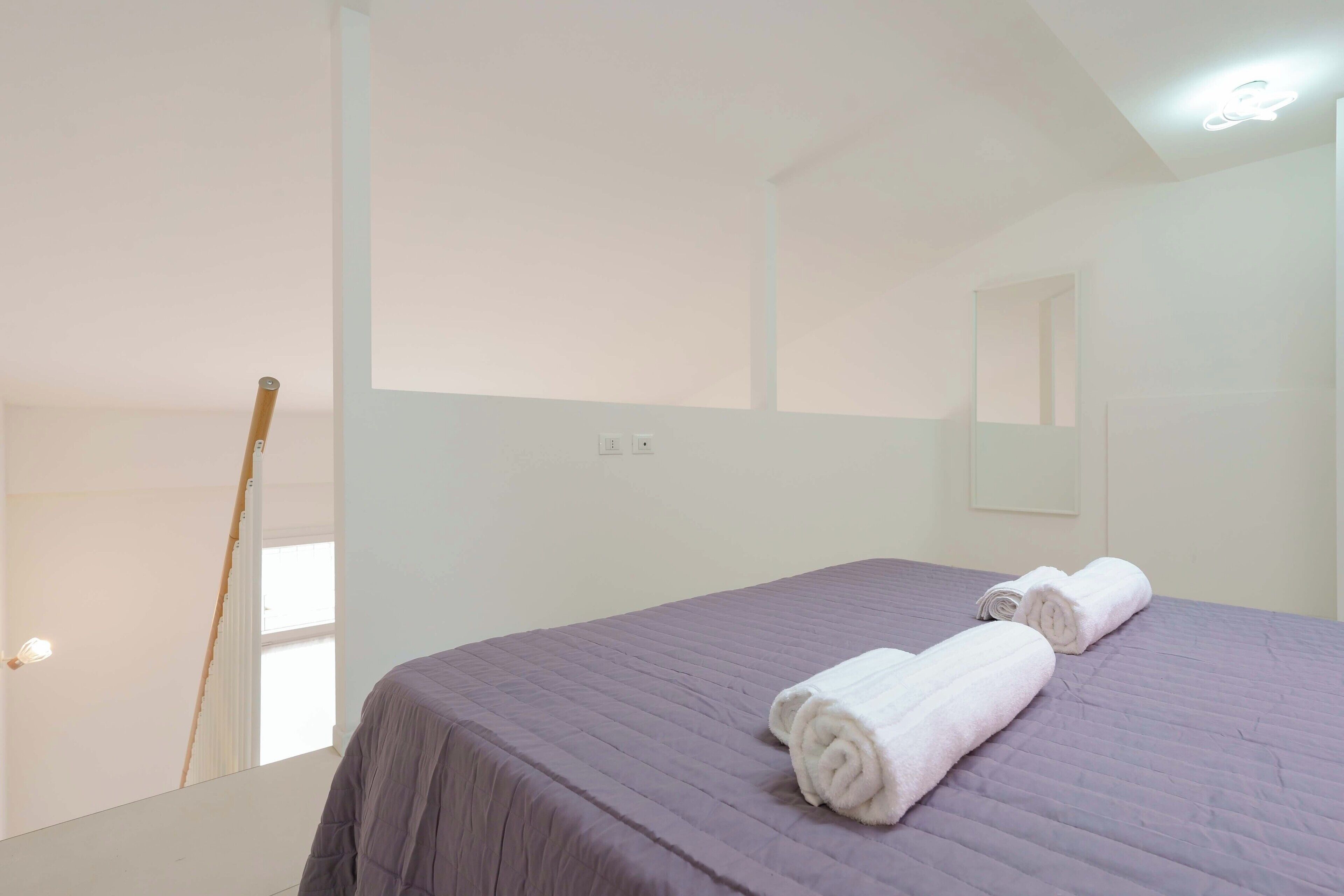 Une chambre d’hôtel avec un lit, une fenêtre et une serviette sur le lit.