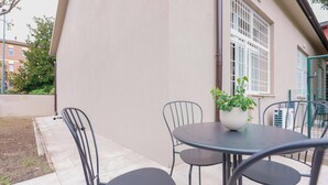 A patio area with a round table and four chairs, a potted plant, and a window with bars. - Casarossoblu- Zona Stadio (Bologna)