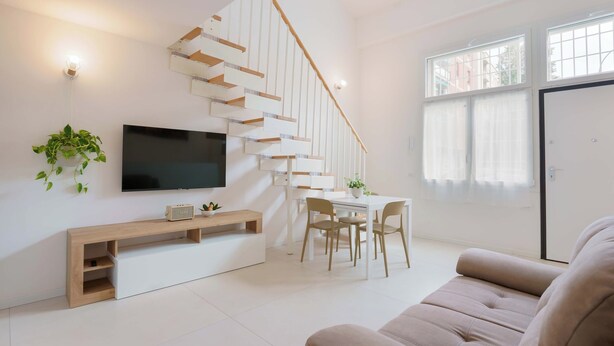 A modern living room with a staircase, a flat-screen TV, a dining area, and a sofa. - Casarossoblu- Zona Stadio (Bologna)
