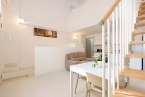 A modern interior with a staircase, a dining area, and a sofa.