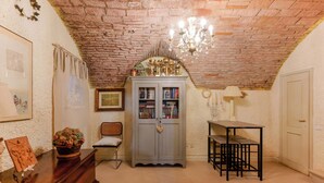 A room with a brick ceiling, a wooden cabinet with glass doors, a table, and a chair. - Gallery Guesthouse (Bologna)