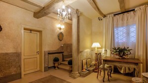 A hallway with a wooden floor, a chandelier, a table with a lamp, and a window with curtains. - Gallery Guesthouse (Bologna)
