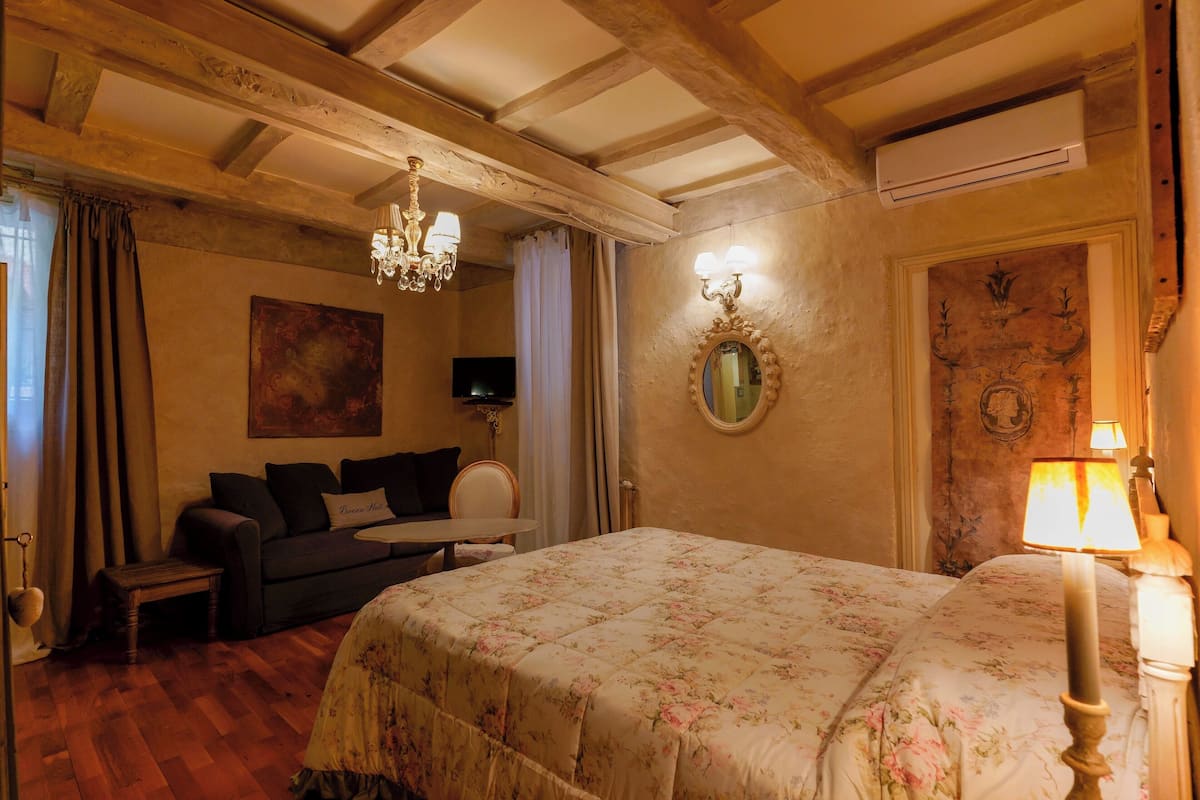 Une chambre d’hôtel avec un grand lit, un canapé, une petite table et un téléviseur.