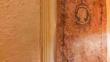 Pared texturizada con un panel decorativo que presenta un marco oval central con un retrato de perfil y follaje circundante.