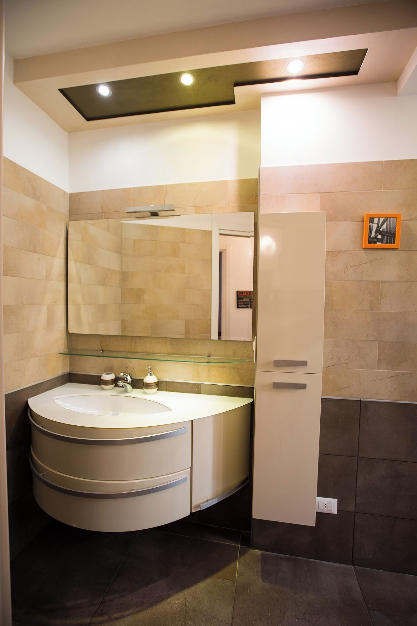 Een moderne badkamer met een gebogen wastafelmeubel, een grote spiegel en een inbouw plafondlamp.