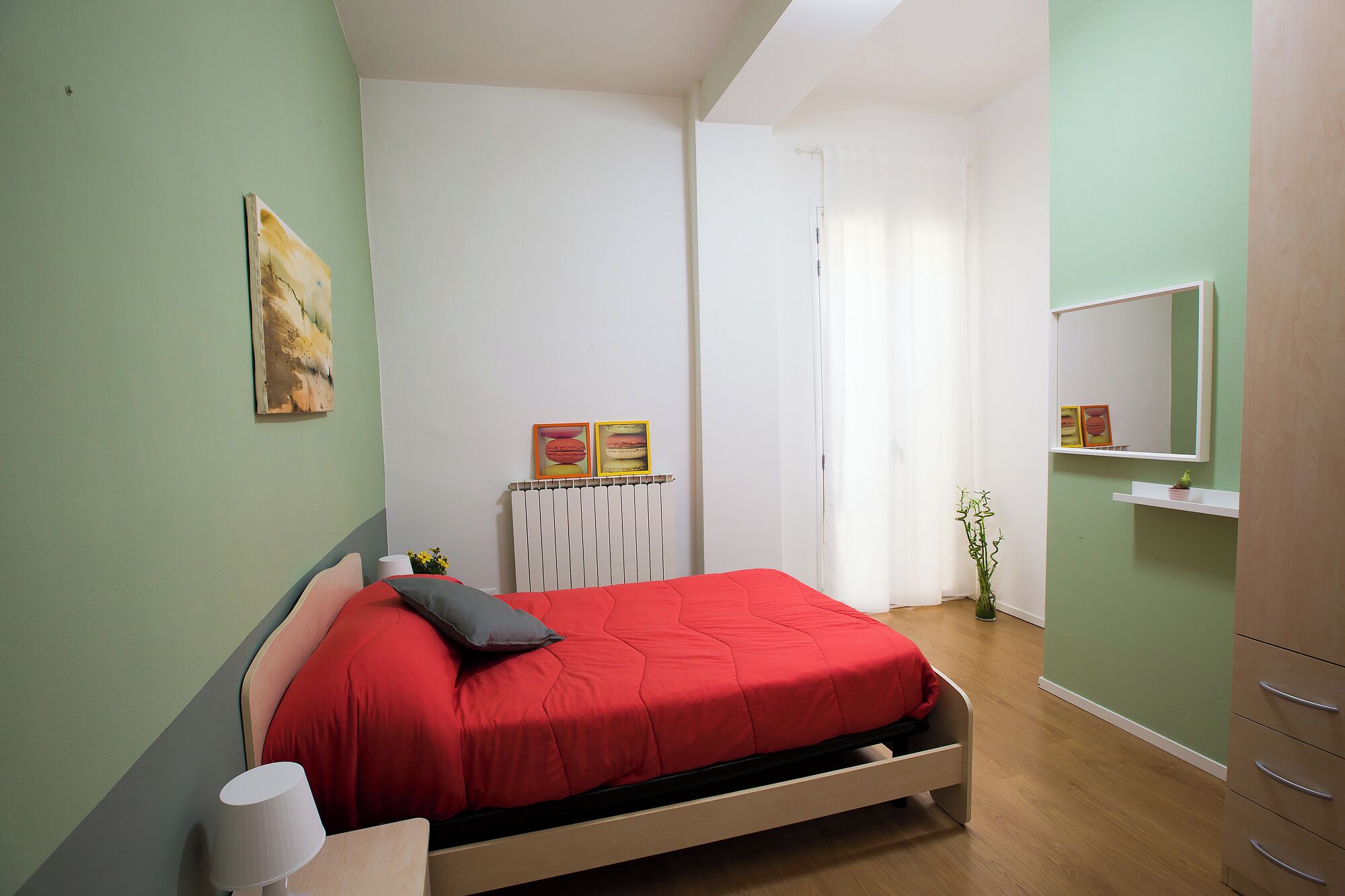 A bedroom with a bed, a radiator, a mirror, and a plant.