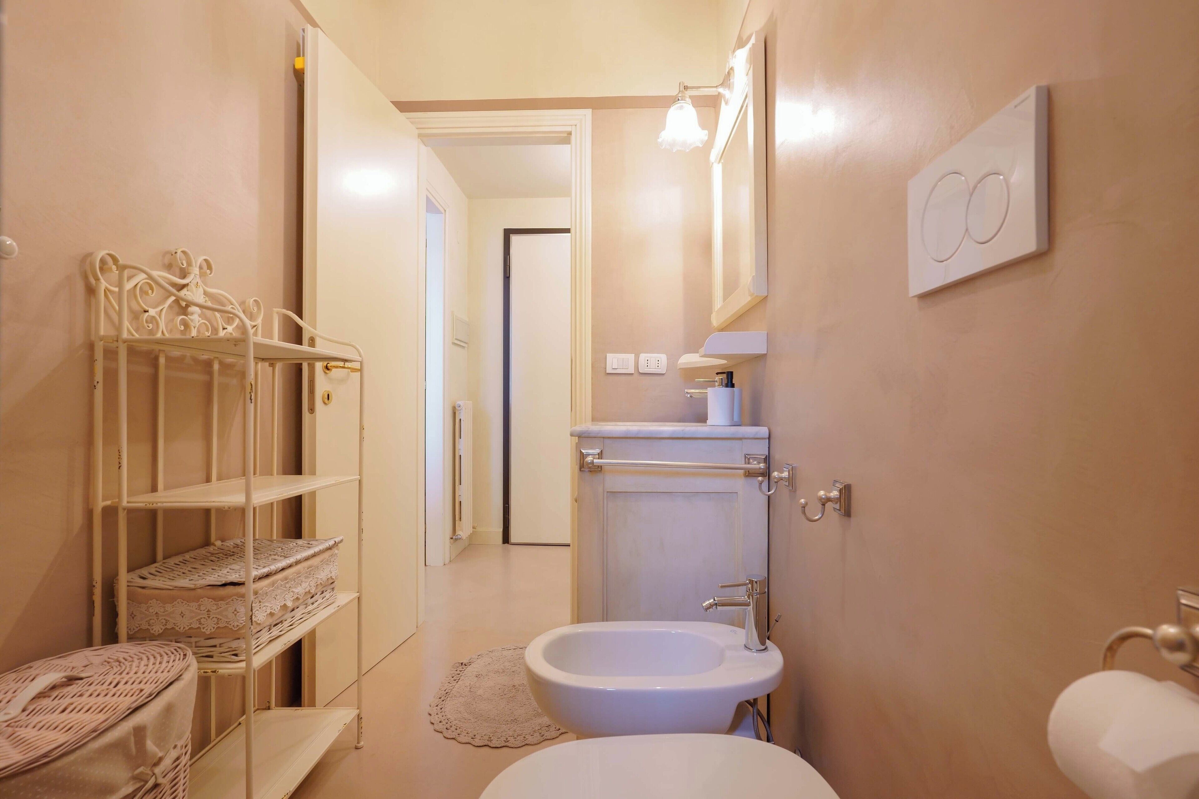 Ein Badezimmer mit einem weißen Waschbecken, einem Bidet, einem Spiegel und einem Ablagefach mit Handtüchern.